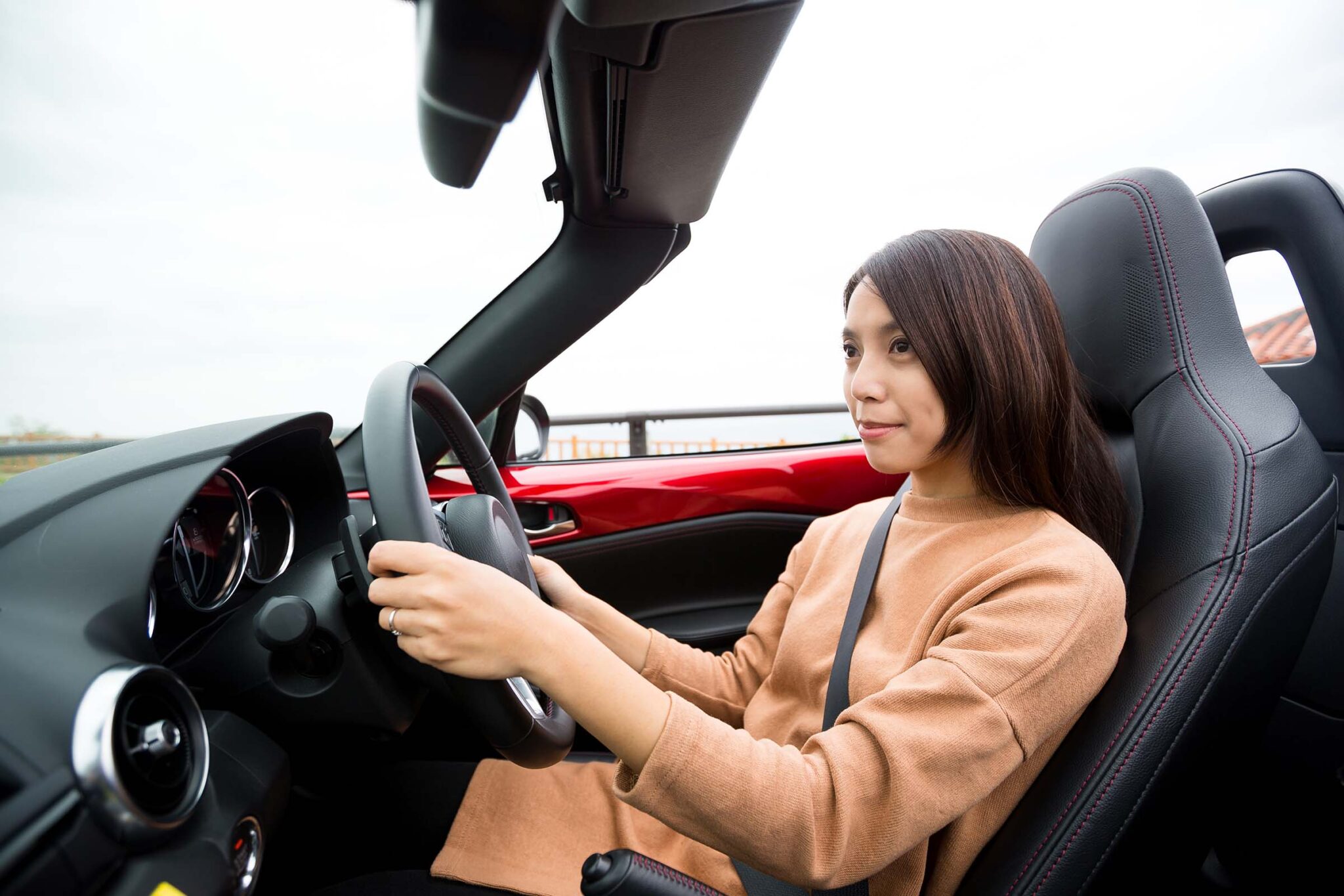 Woman driving a red convertible car.